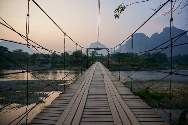 wooden bridge hanging on many ropes across a river