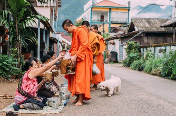 monks collecting alms from Buddhist in Vang Vieng