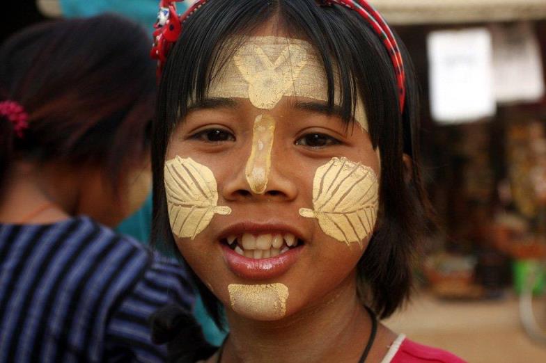 a girl with white Thanakha powder on her cheeks, chin and forehead