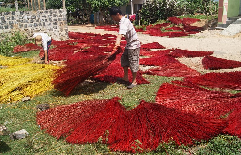 a man is coloring straws to makw colored sedge mat