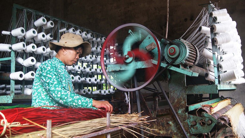 a woman is weaving sedge mats