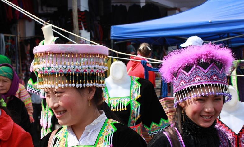 two women wearing beautiful flower hats that are the signature of their ethnic